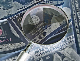 A magnifying glass over $20 notes.